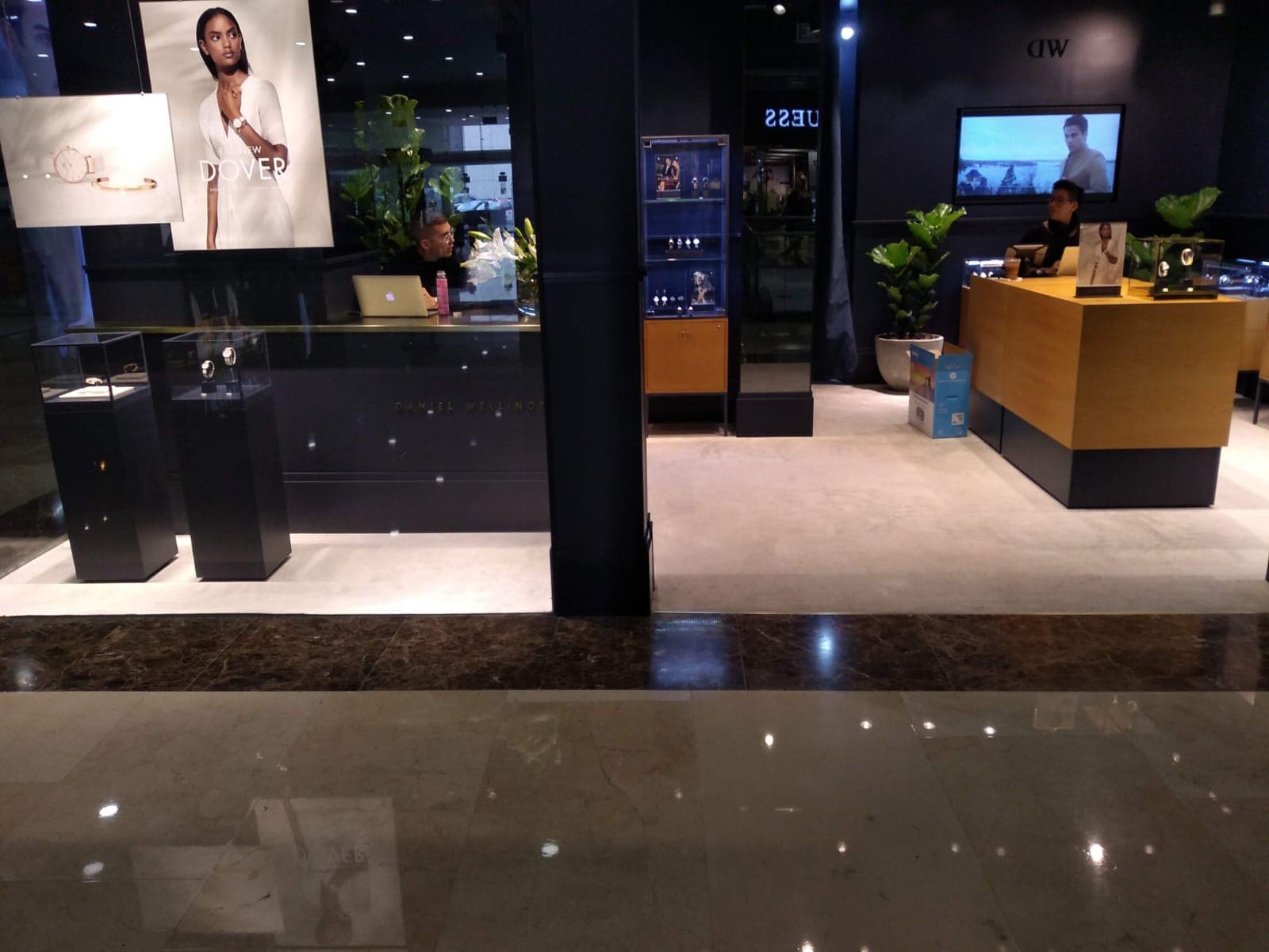 Interior de centro comercial con tiendas y acceso principal